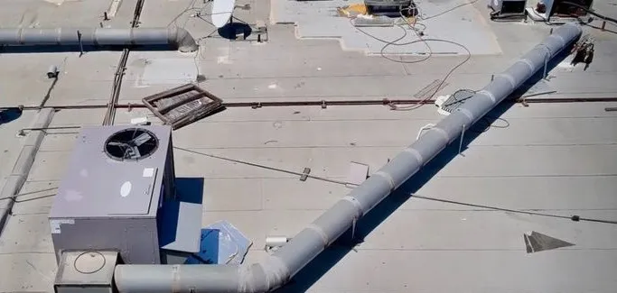 Aerial view of a commercial flat roof with weathered surfacing around large duct runs