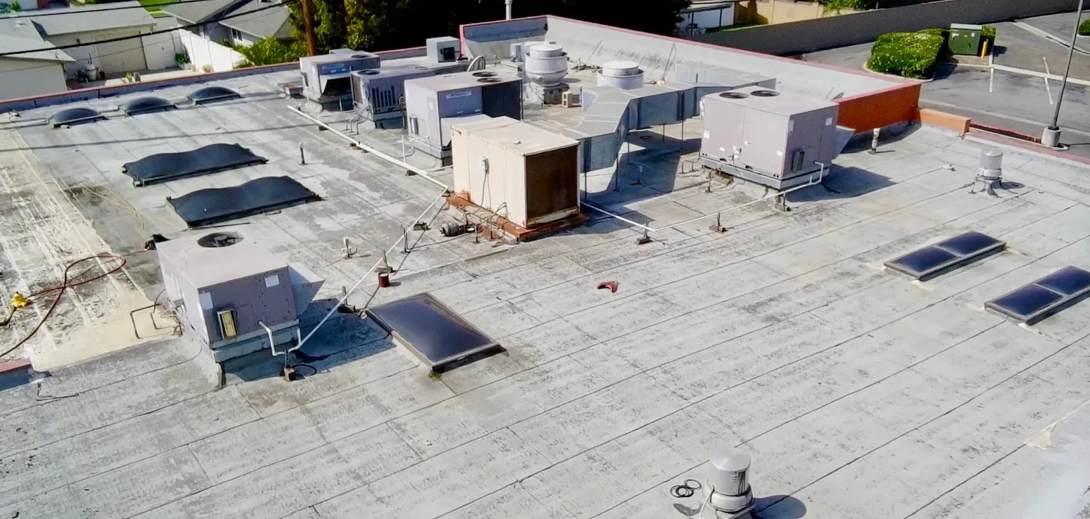 Aerial view of a weathered commercial flat roof with stained, patched surfacing