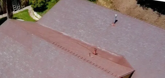 Aerial view of a home with faded red shingles weathered pale before the re-roof