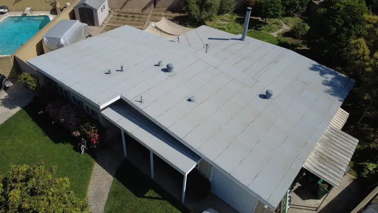 Aerial view of a completed flat-roof home beside a backyard pool
