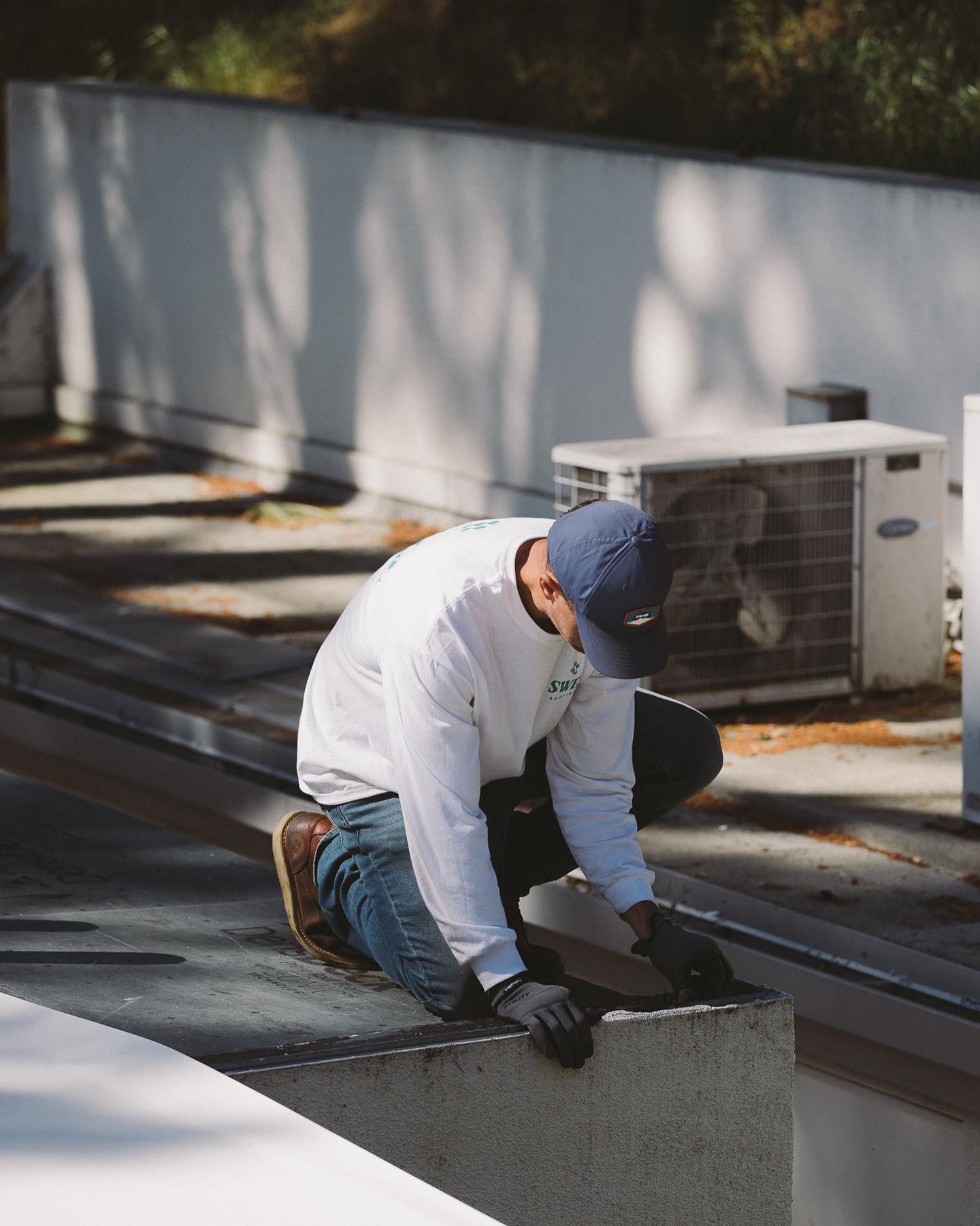 Asa Wolfe inspecting a commercial parapet corner near rooftop equipment