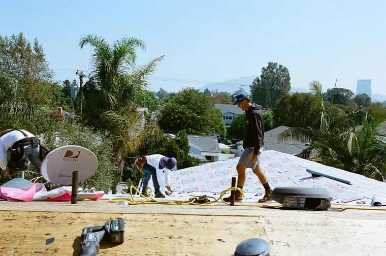 Crew installing underlayment on a pitched residential roof
