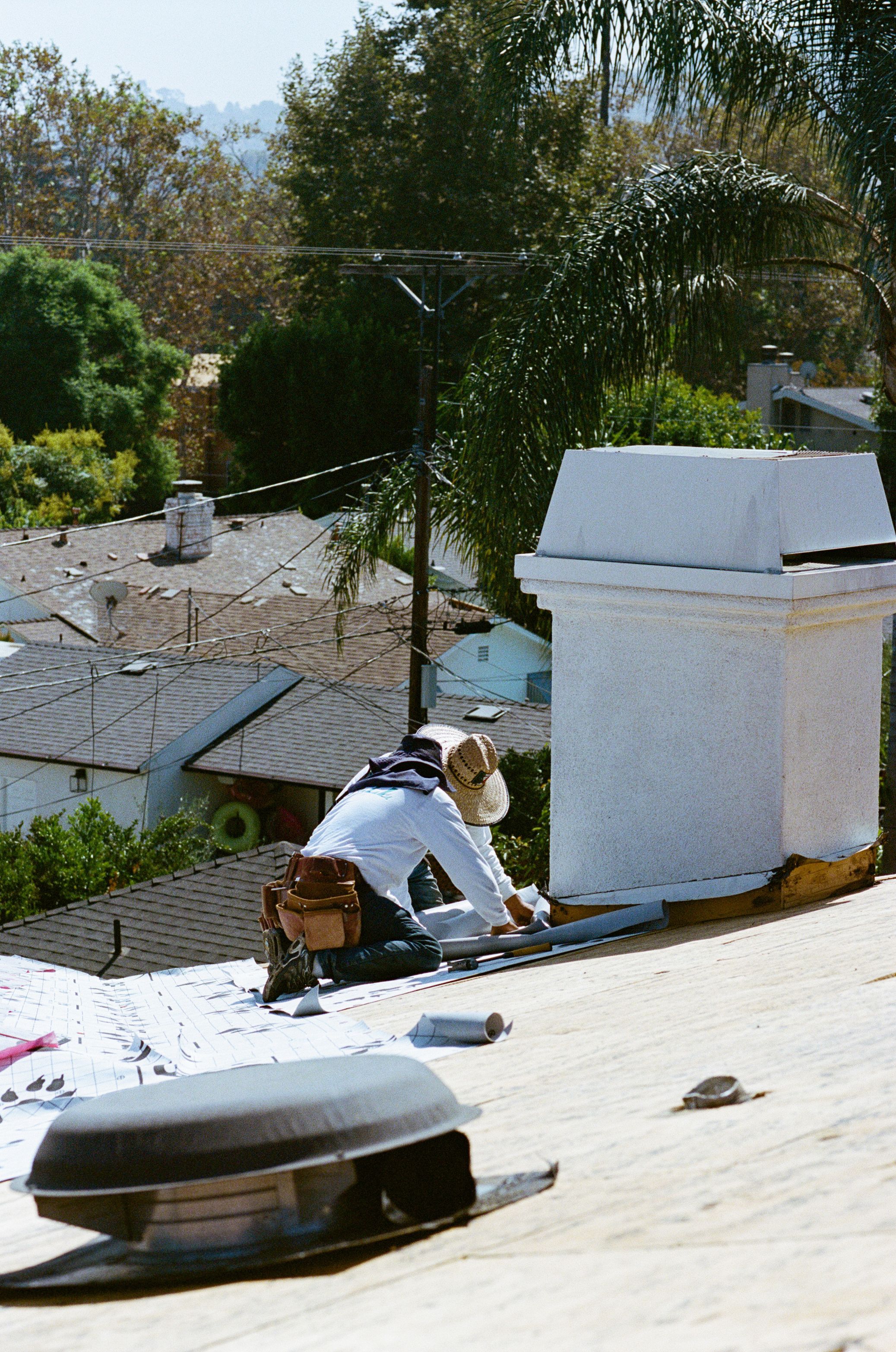 Swell roofer repairing flashing around a chimney and roof vent