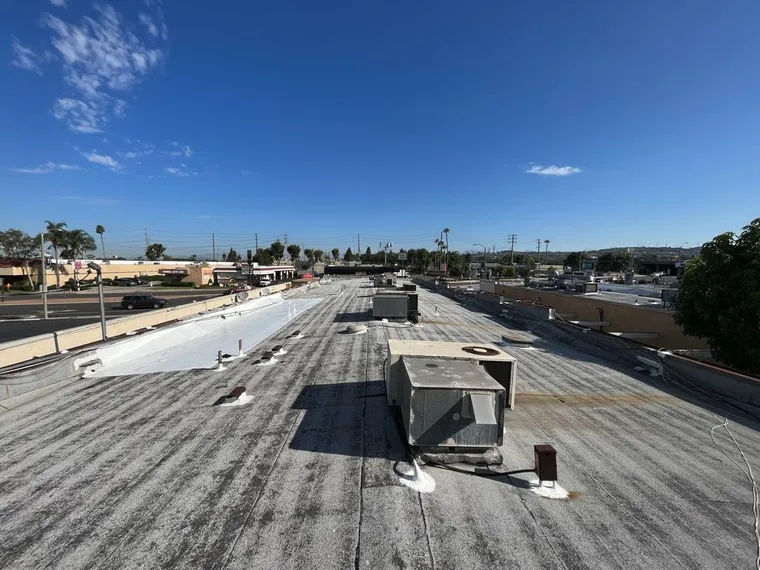Weathered commercial gravel roof with HVAC curbs before restoration