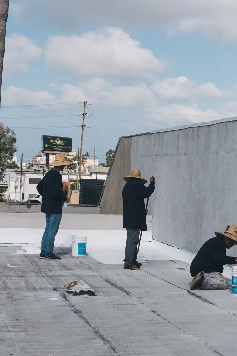 Three-person crew coating a commercial flat roof