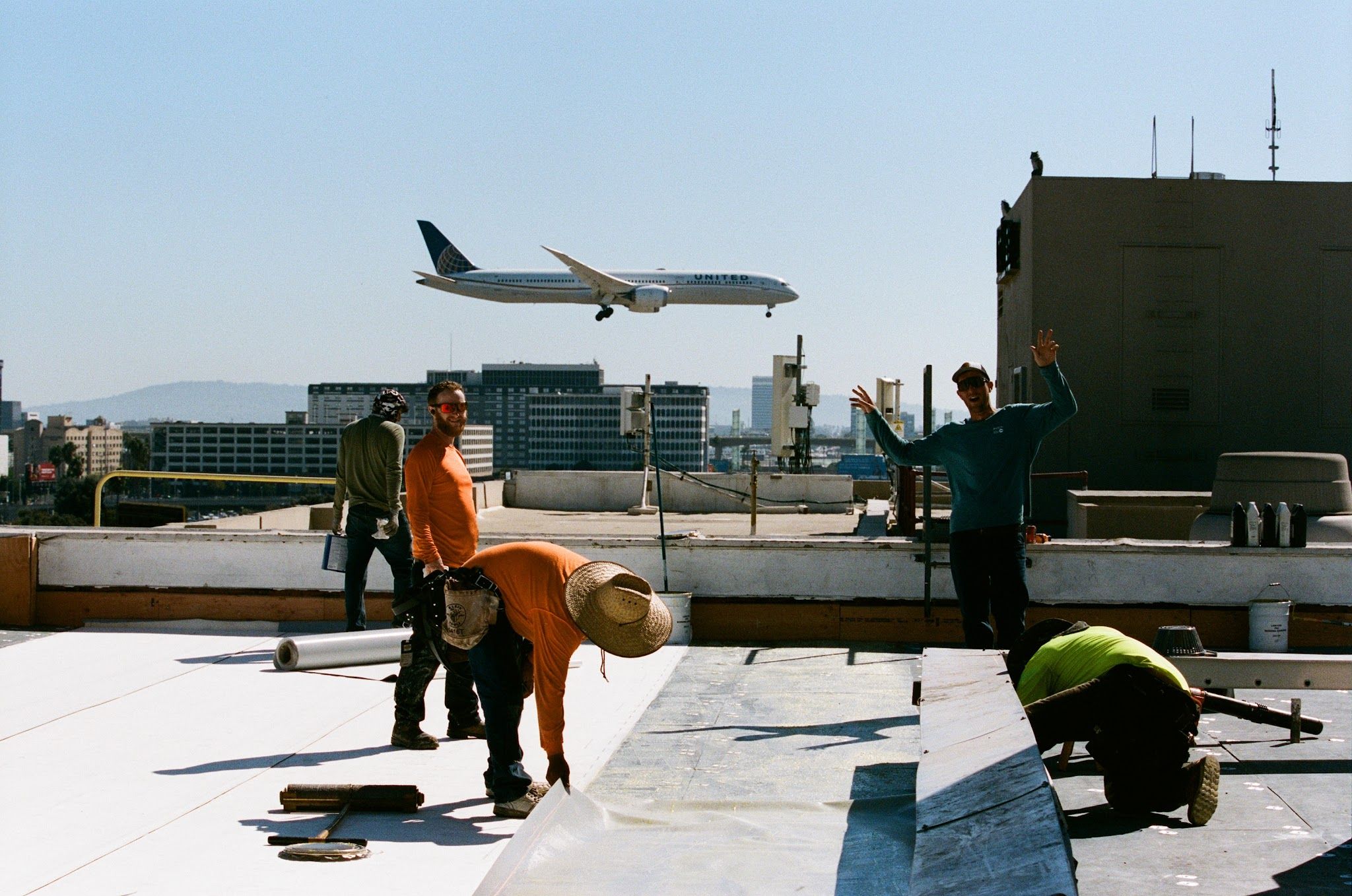 Swell Roofing crew working on a commercial flat roof as a jet approaches LAX