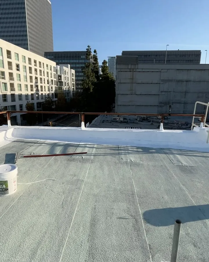 Roller work in progress on a white roof overlooking Downtown Los Angeles