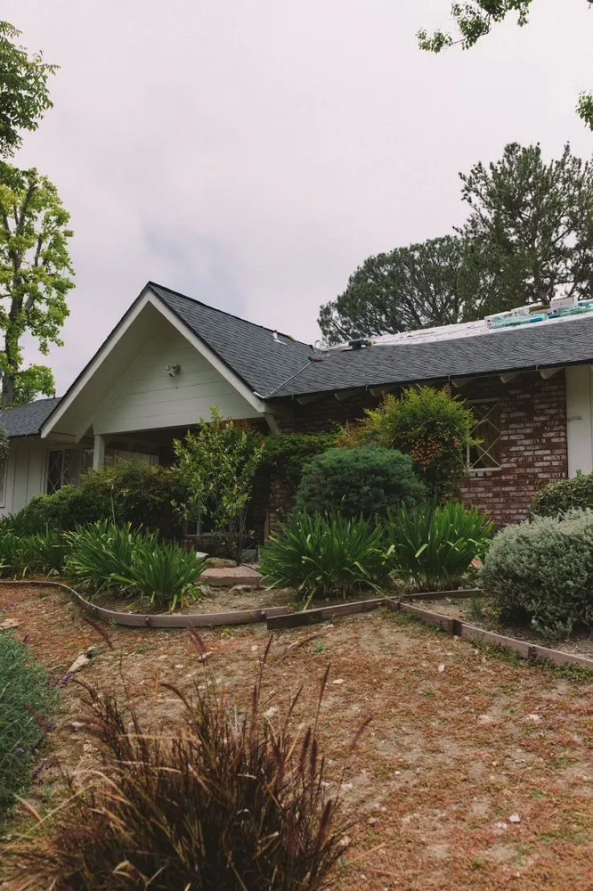 Ranch house with a finished charcoal shingle roof and drought-tolerant garden