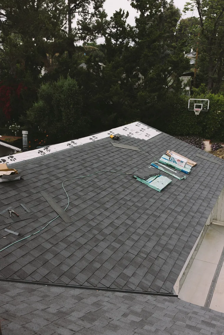 Finished charcoal shingle roof viewed from the ridge above a driveway