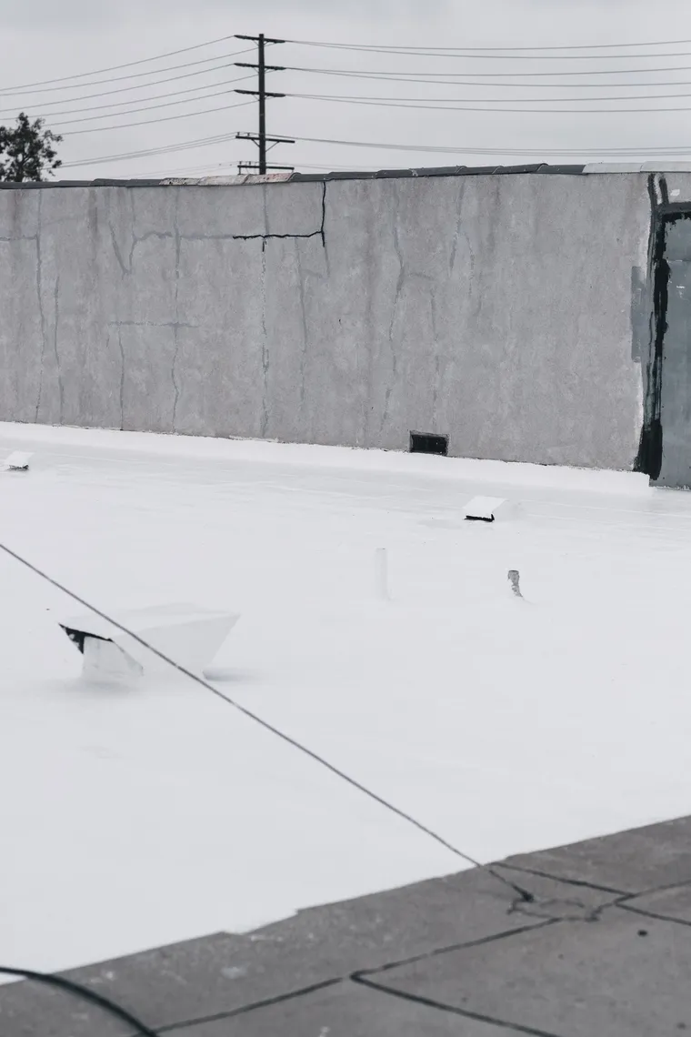 Completed white-coated flat roof with vents and rooftop equipment
