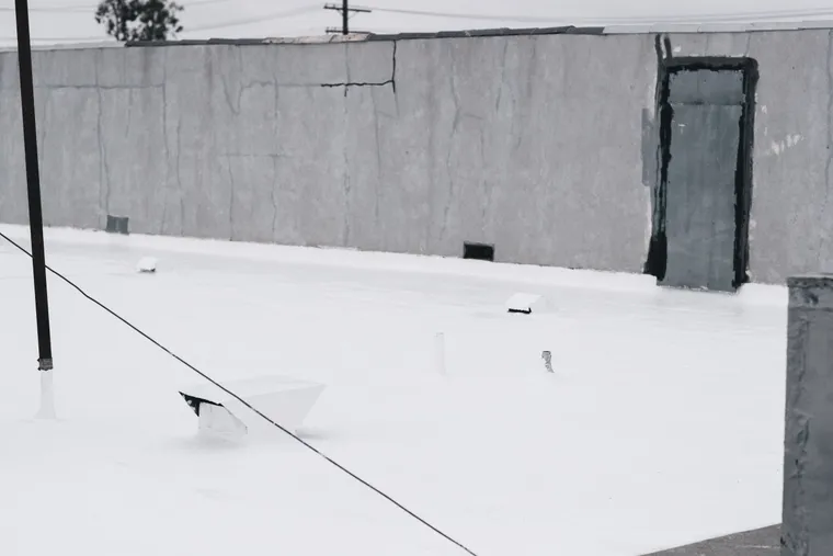 Finished white roof coating around parapets and vent penetrations
