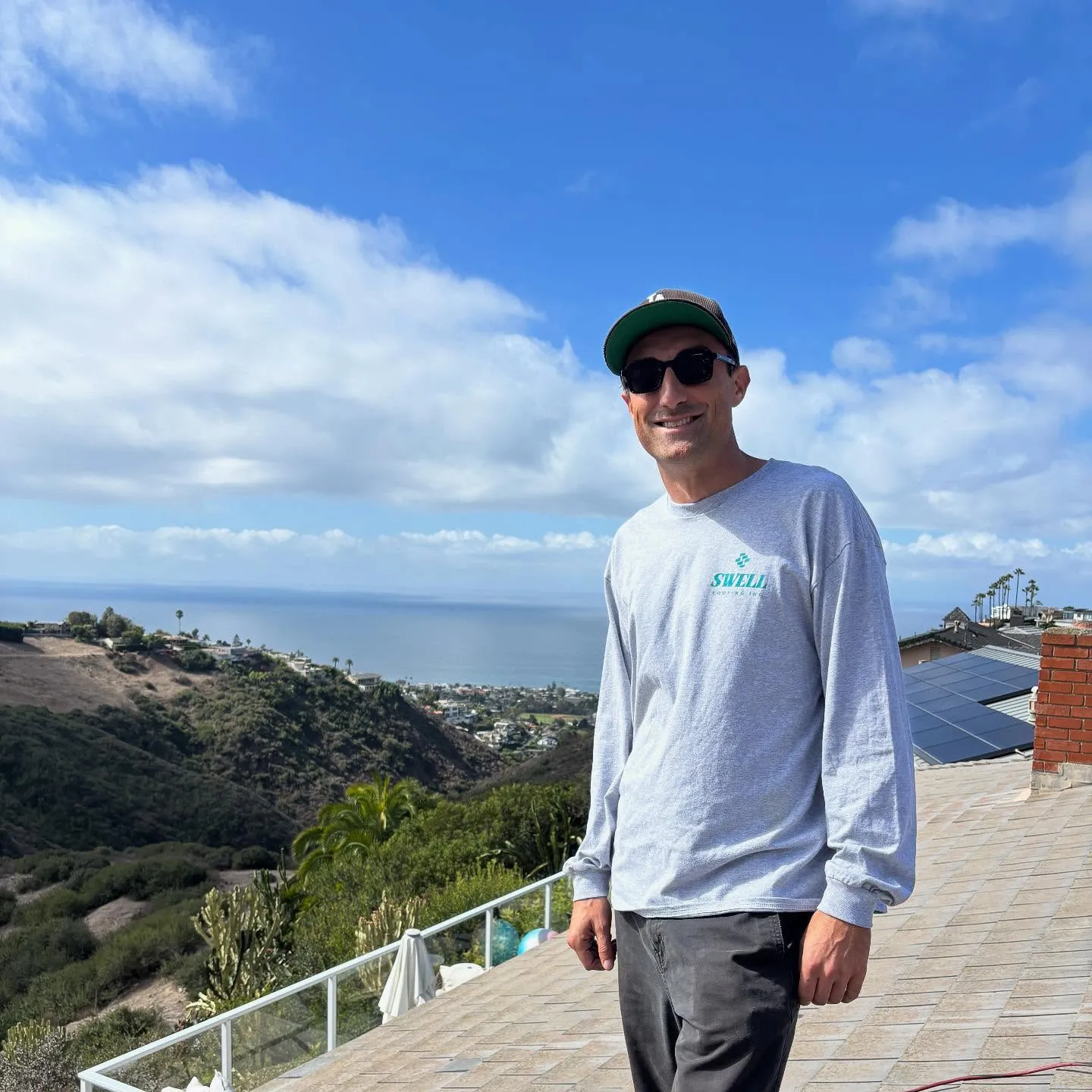 Swell roofer standing on a coastal roof with the ocean beyond