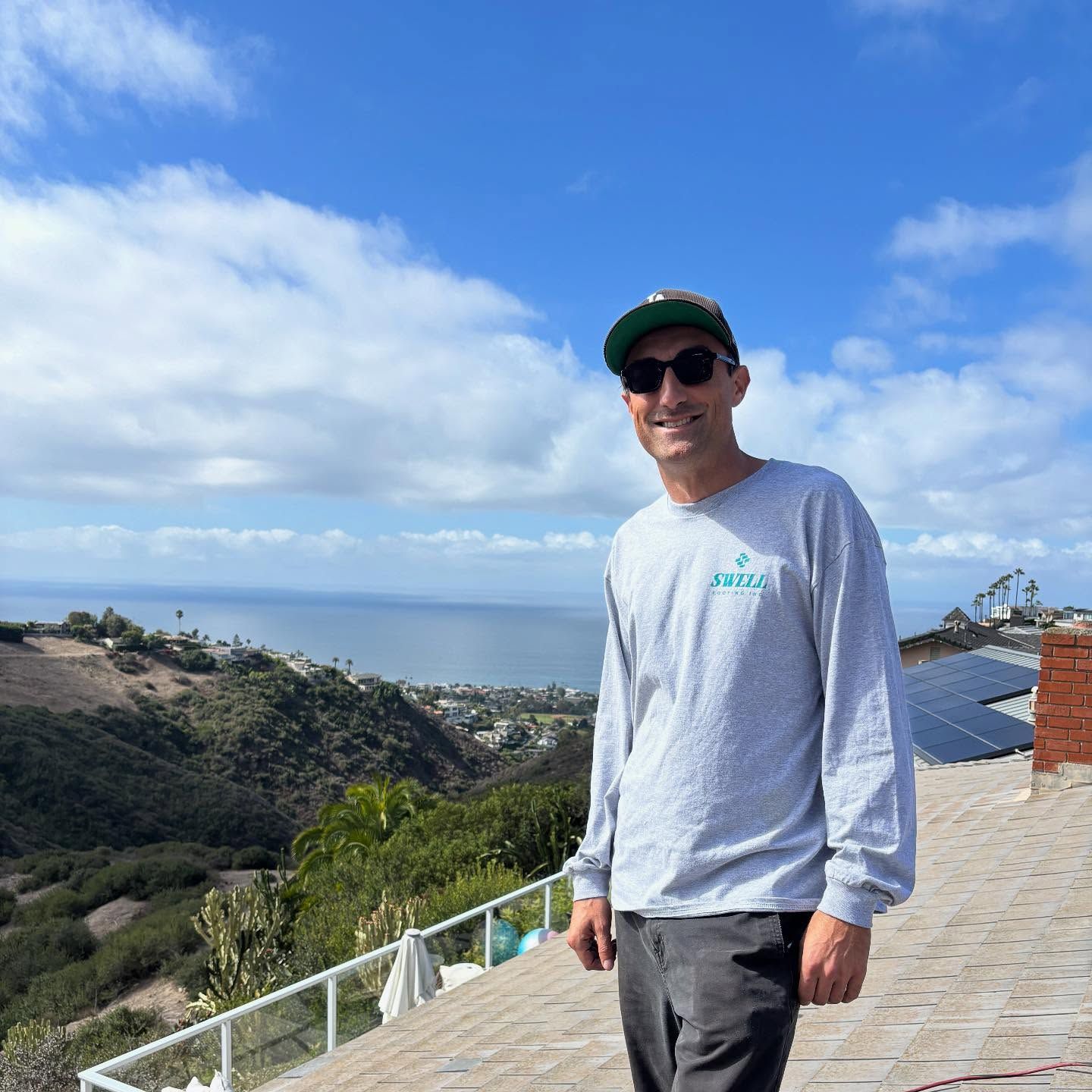 Swell roofer standing on a coastal roof with the ocean beyond