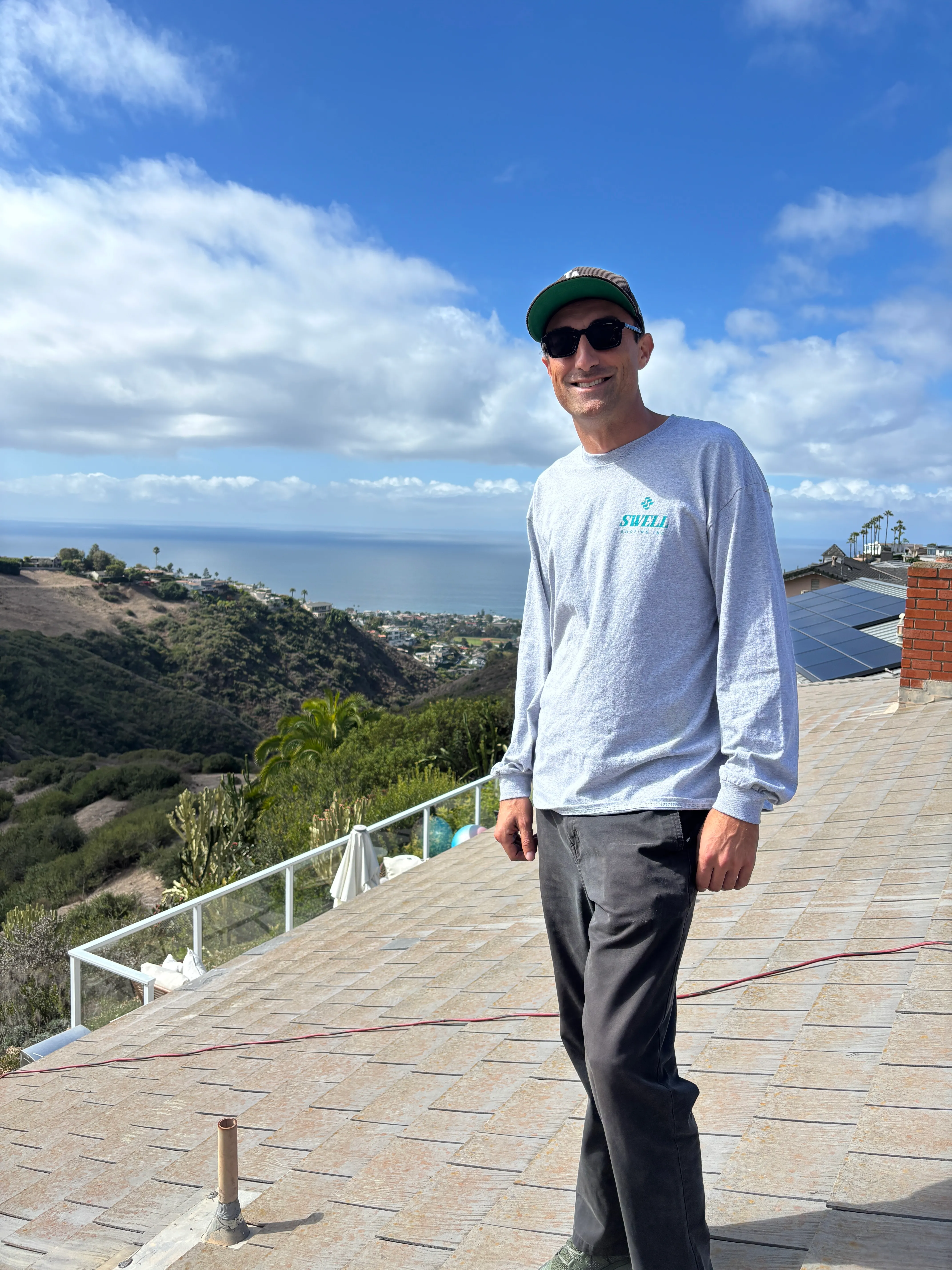 Jonny standing on a residential roof with the Southern California coast behind him