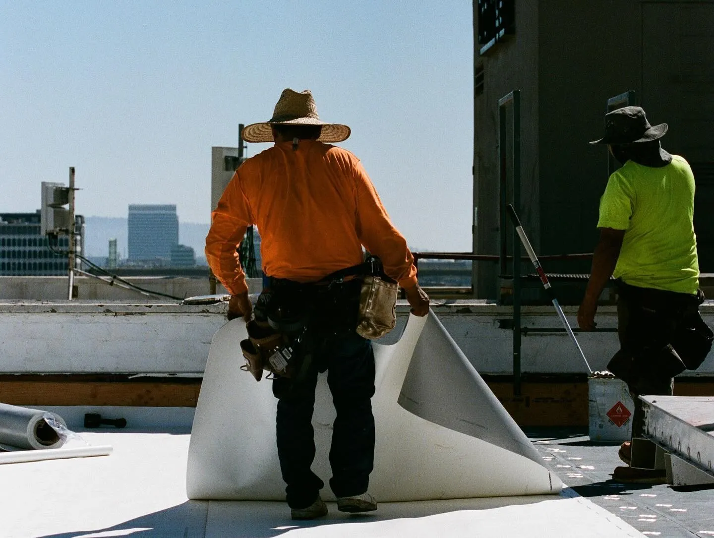 Crew rolling membrane beside a commercial roof parapet