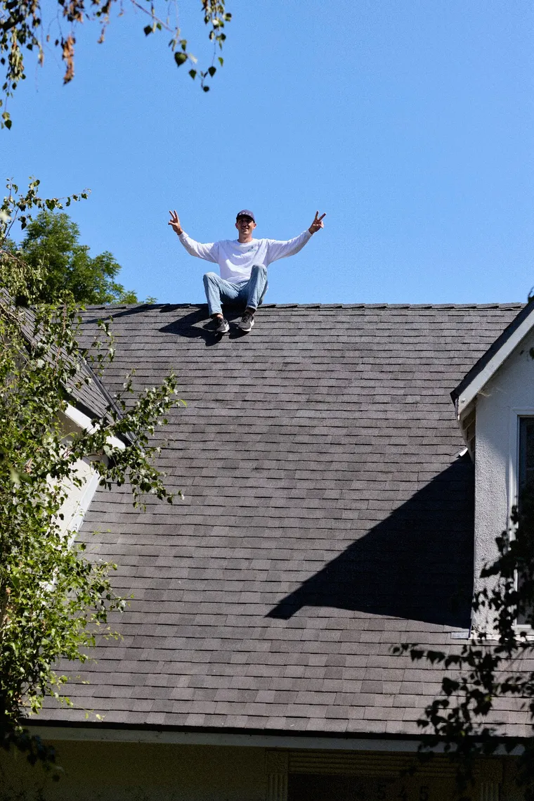 Swell roofer posing on a newly finished charcoal shingle roof