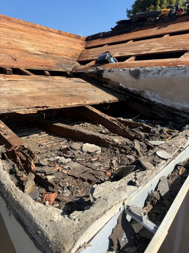 Close view of rotted roof decking exposed during tear-off