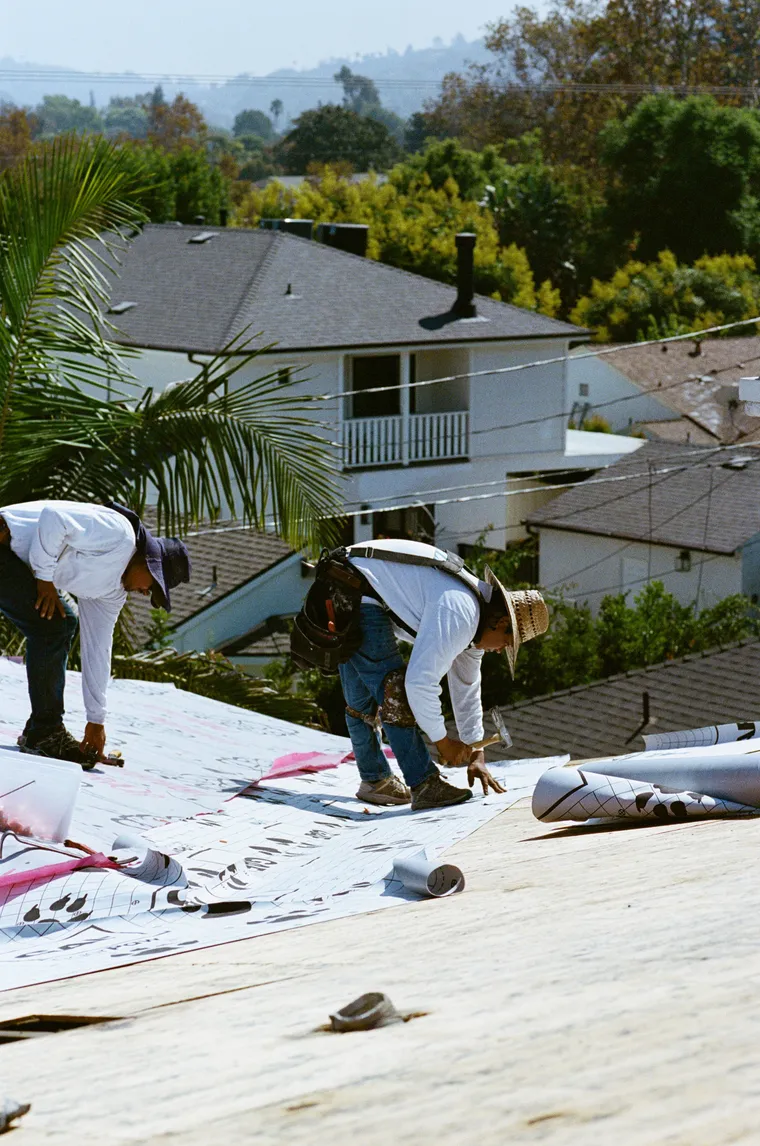 Two roofers installing underlayment together on a pitched roof