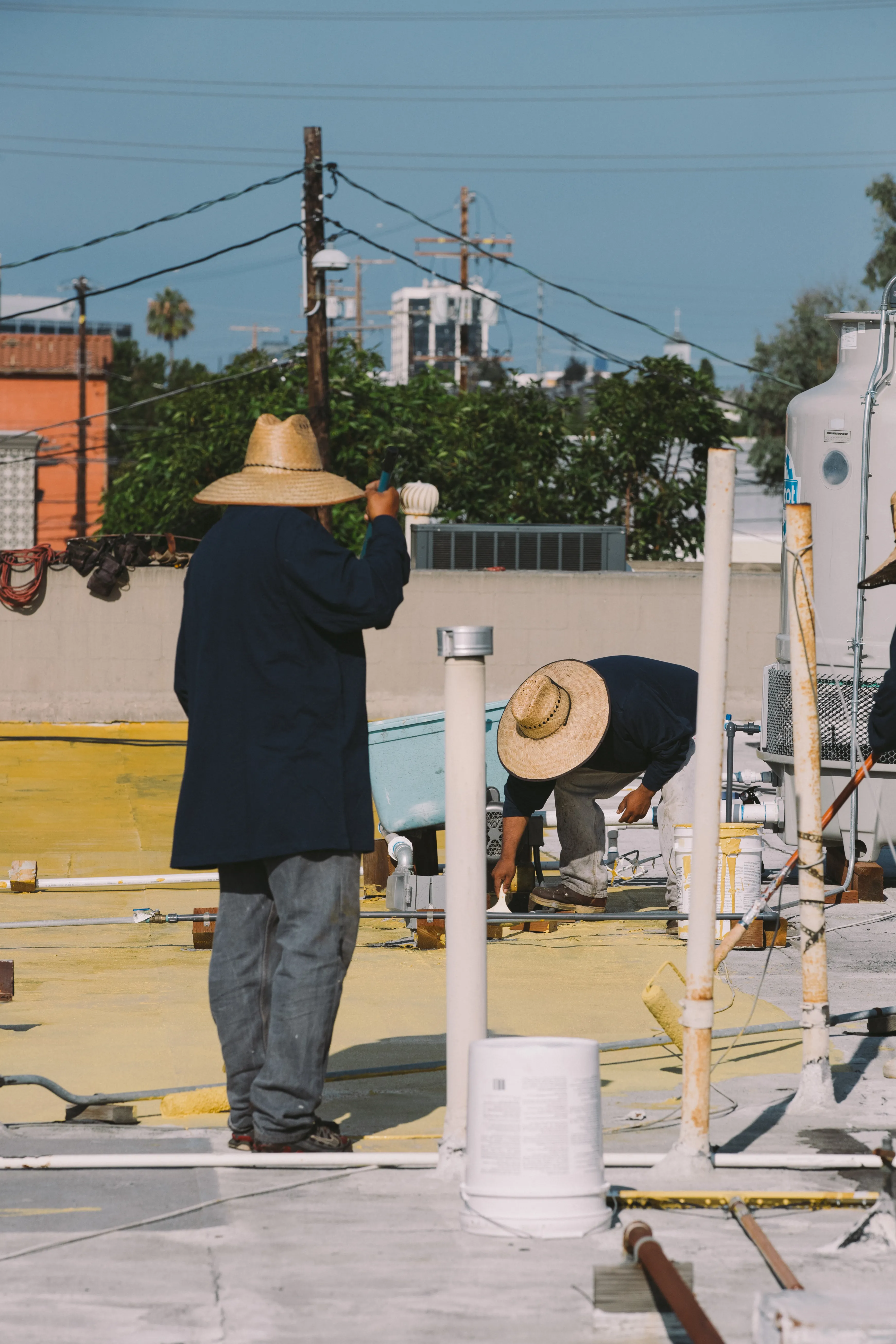 Two Swell roofers working around vent pipes on a commercial flat roof