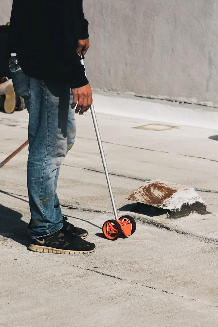 Roofer using a measuring wheel across a commercial flat roof