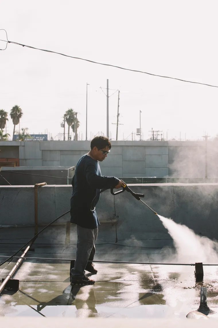 Worker cleaning a flat roof with a pressure washer